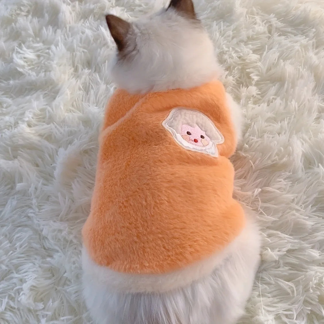 Soft fleece cat vest for winter in orange with a cute design on the back