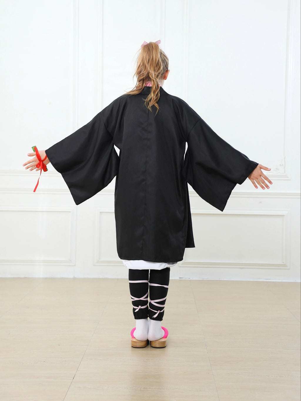 Girl wearing a black anime kimono cosplay costume with wide sleeves and traditional style