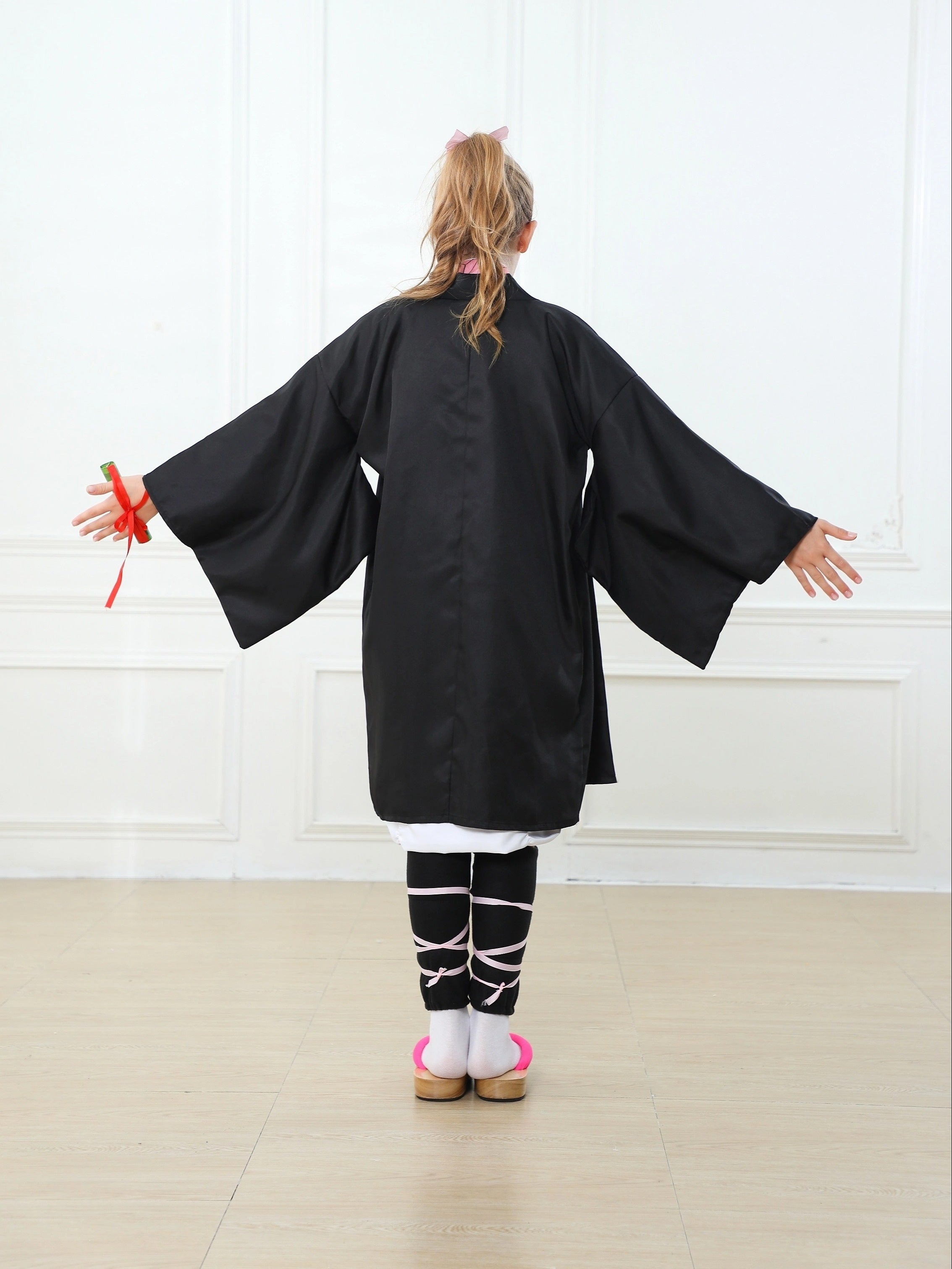 Girl wearing a black anime kimono cosplay costume with wide sleeves and traditional style
