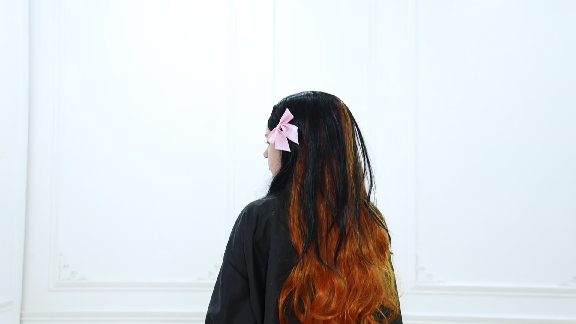 Model wearing anime kimono cosplay costume with long black and orange hair and a pink bow