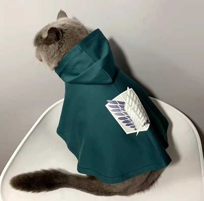 Cat wearing an Attack on Titan pet cosplay costume with a hood and logo on the back