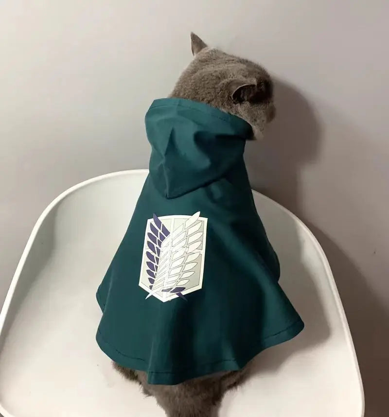 Cute cat wearing an Attack on Titan pet cosplay costume with a green hooded cape.