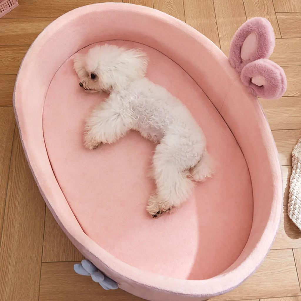 Small white dog relaxing in a pink CloudNest Detachable Pet Bed with soft cushioning