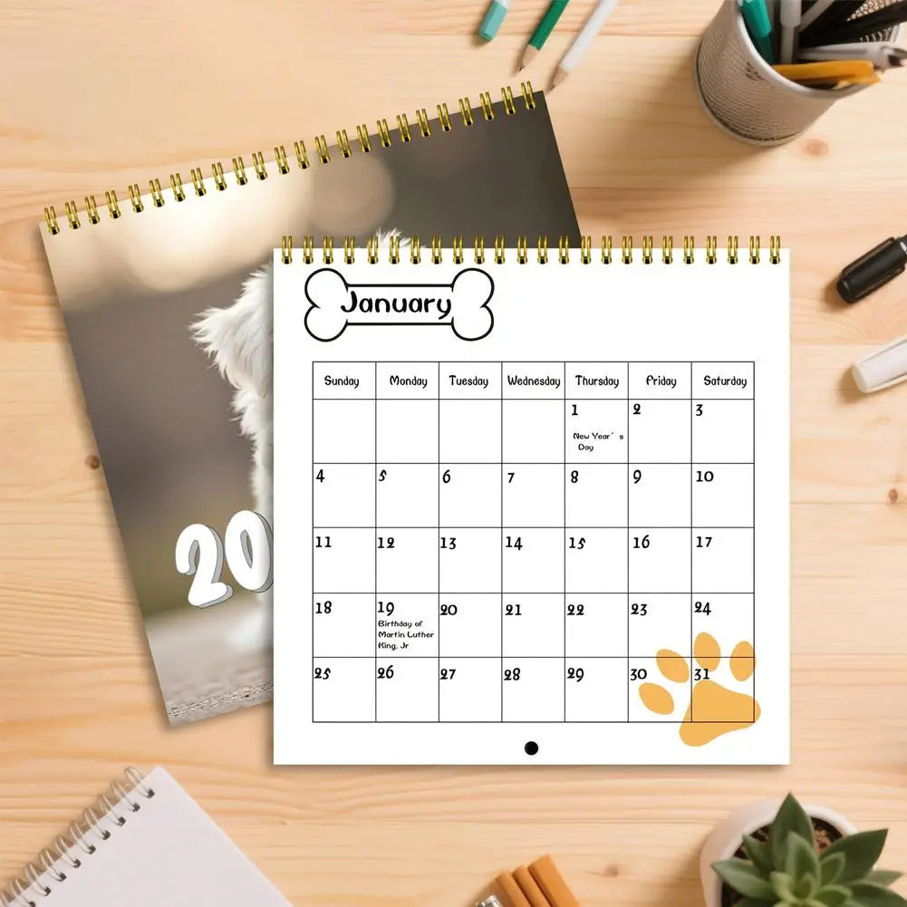 Cute puppy wall calendar 2026 displayed on a wooden table with stationery for dog lovers