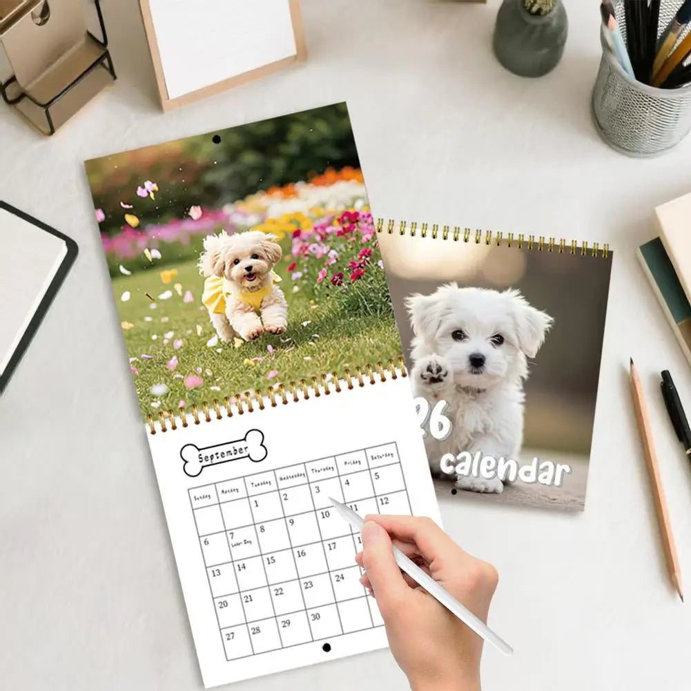 Cute puppy wall calendar 2026 displayed on a desk with flowers and a handwritten note
