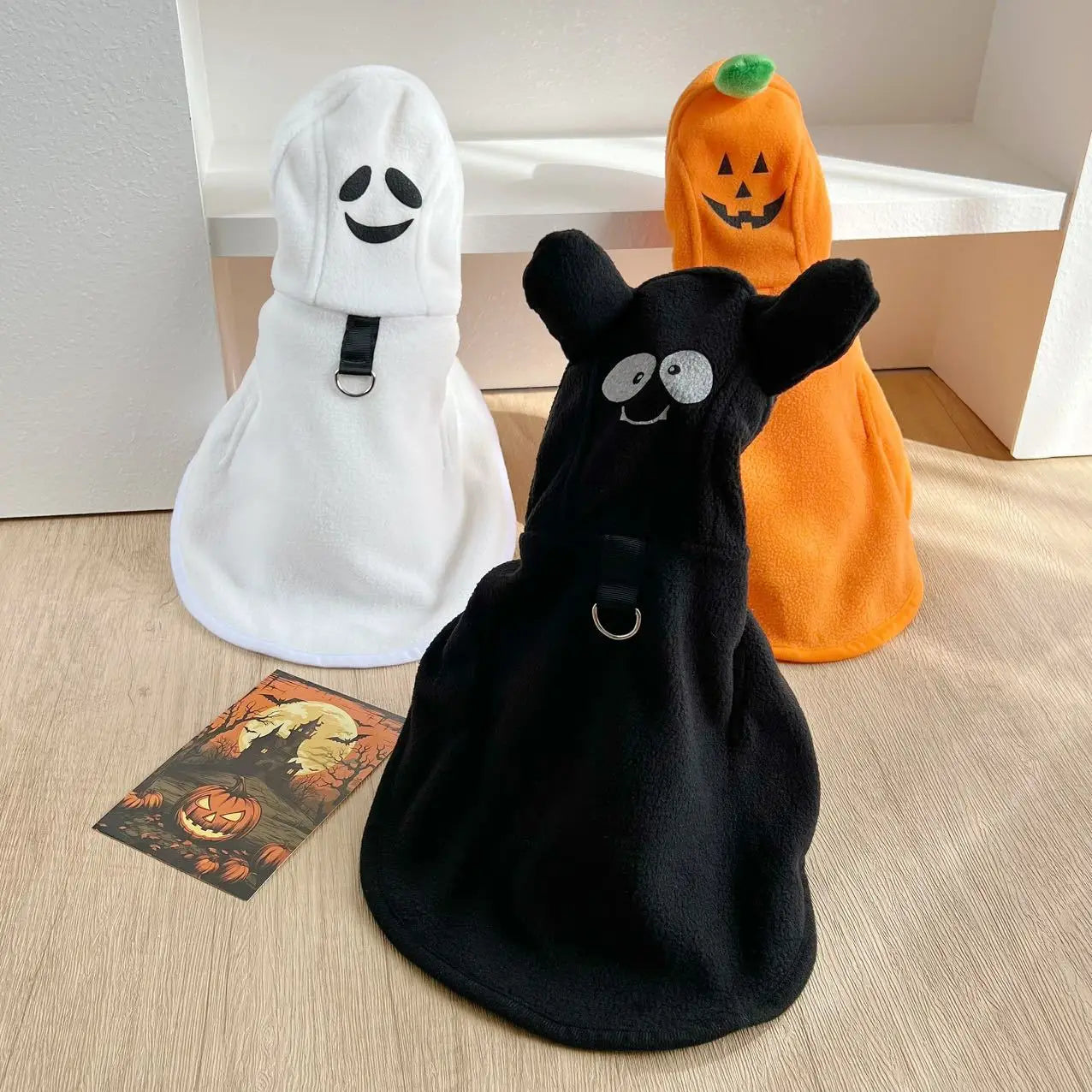 Three adorable pet costumes featuring a white ghost, black ghost, and orange pumpkin dog Halloween ghost cape