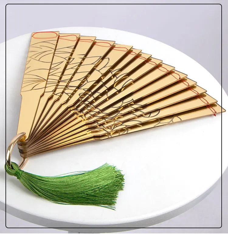Gold Douma cosplay folding fan with intricate designs and a green tassel for anime enthusiasts