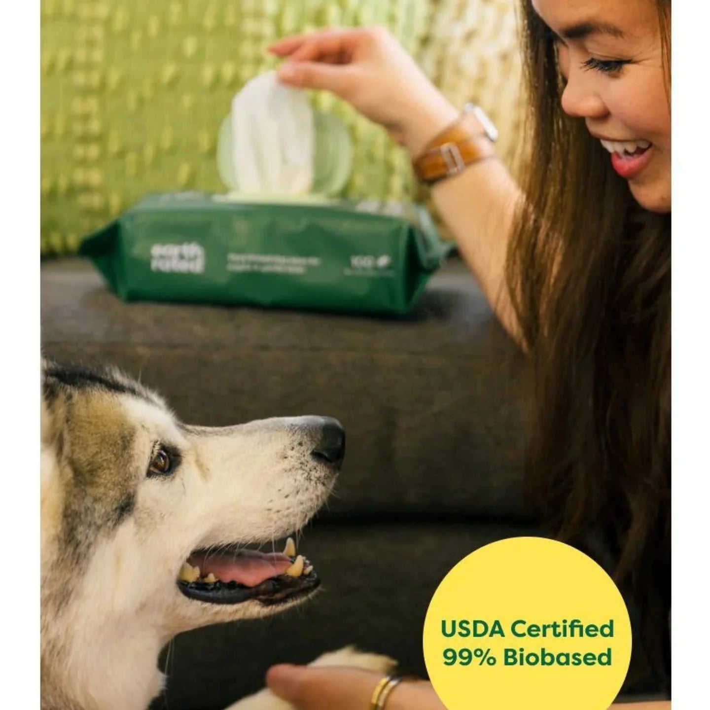 Woman using earth rated pet wipes to clean happy dog with package visible in background