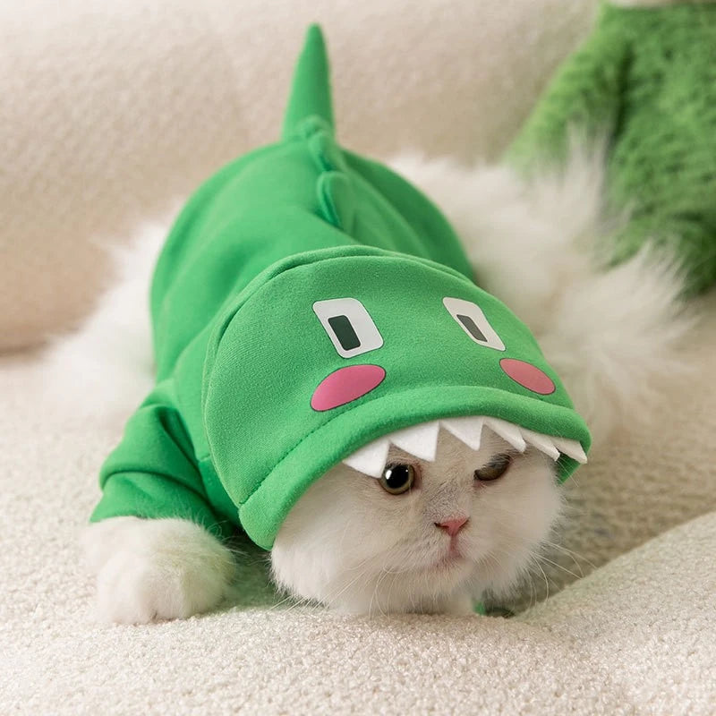 Adorable white cat wearing a green dinosaur funny animal costume for pets with a hood and tail