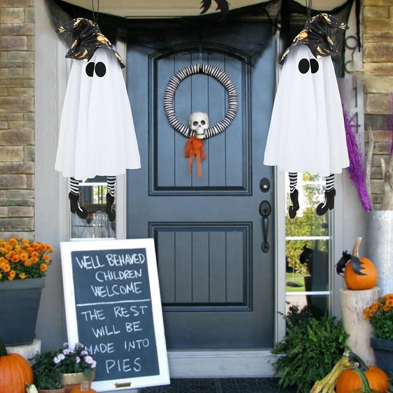 Halloween LED witch ghost decorations hanging by a front door with a festive wreath and pumpkins
