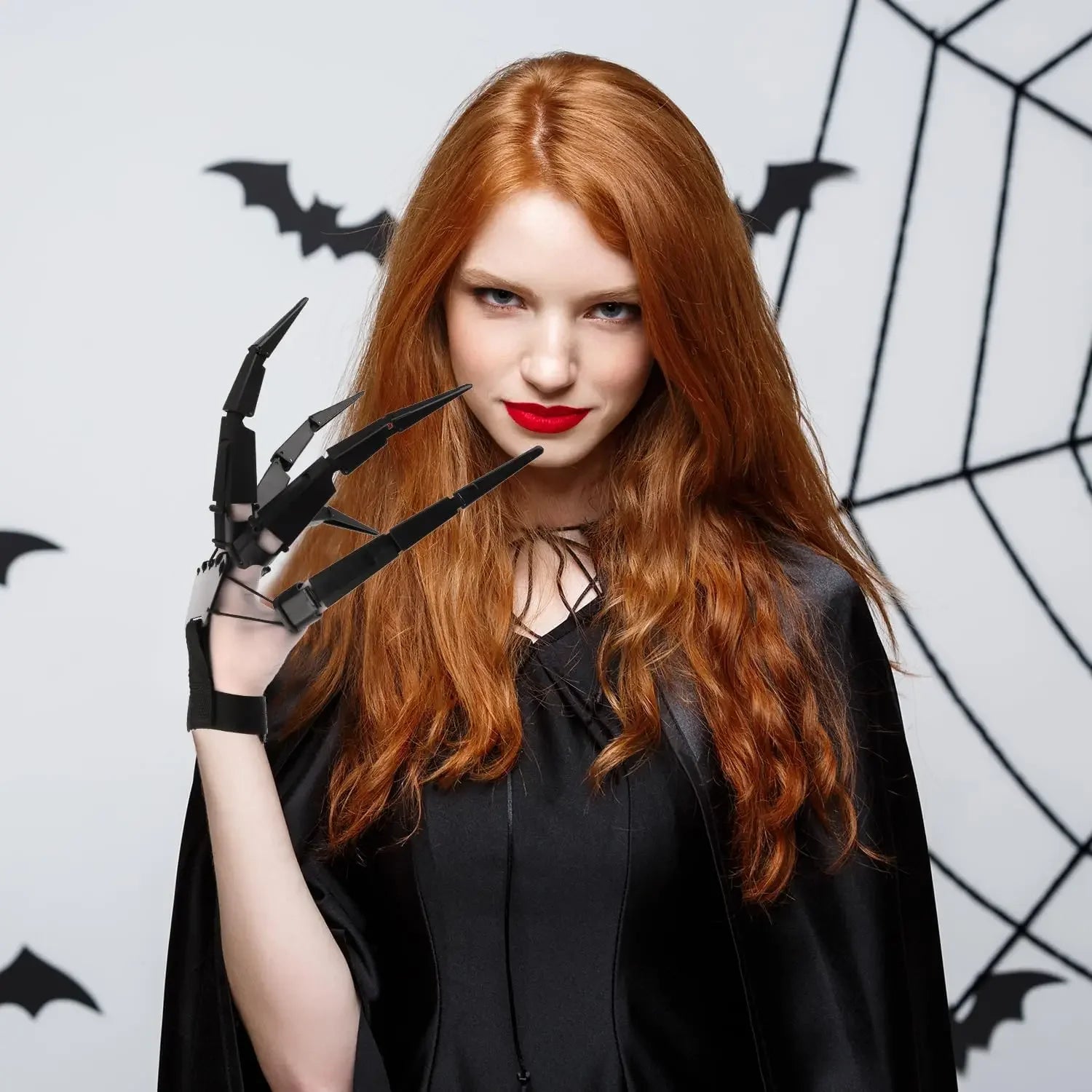 Halloween pet skeleton hand costume worn by a model with red hair in a black cape