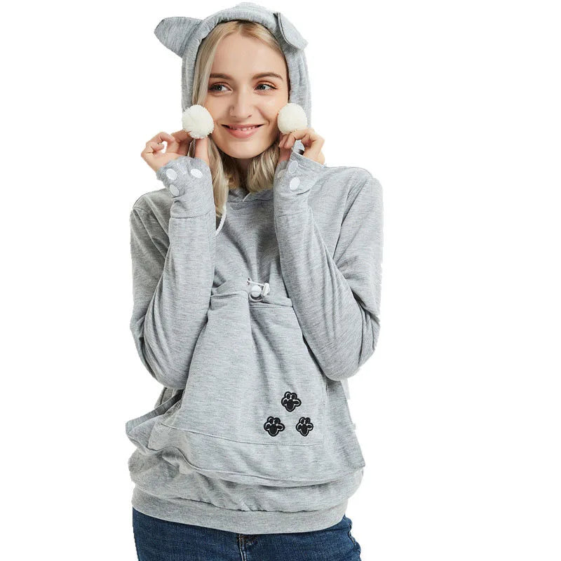 Woman wearing a comfy pet carrier kangaroo sweatshirt with cute hood and pom-pom details.