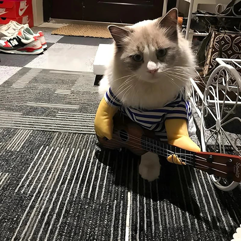 Cat wearing a pet guitar costume holding a toy guitar, dressed in a striped shirt