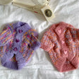Two puppy knitted coats for winter in purple and pink, featuring heart-shaped buttons and cozy textures