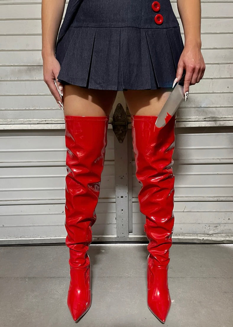 Model wearing shiny red over the knee boots paired with a stylish grey skirt