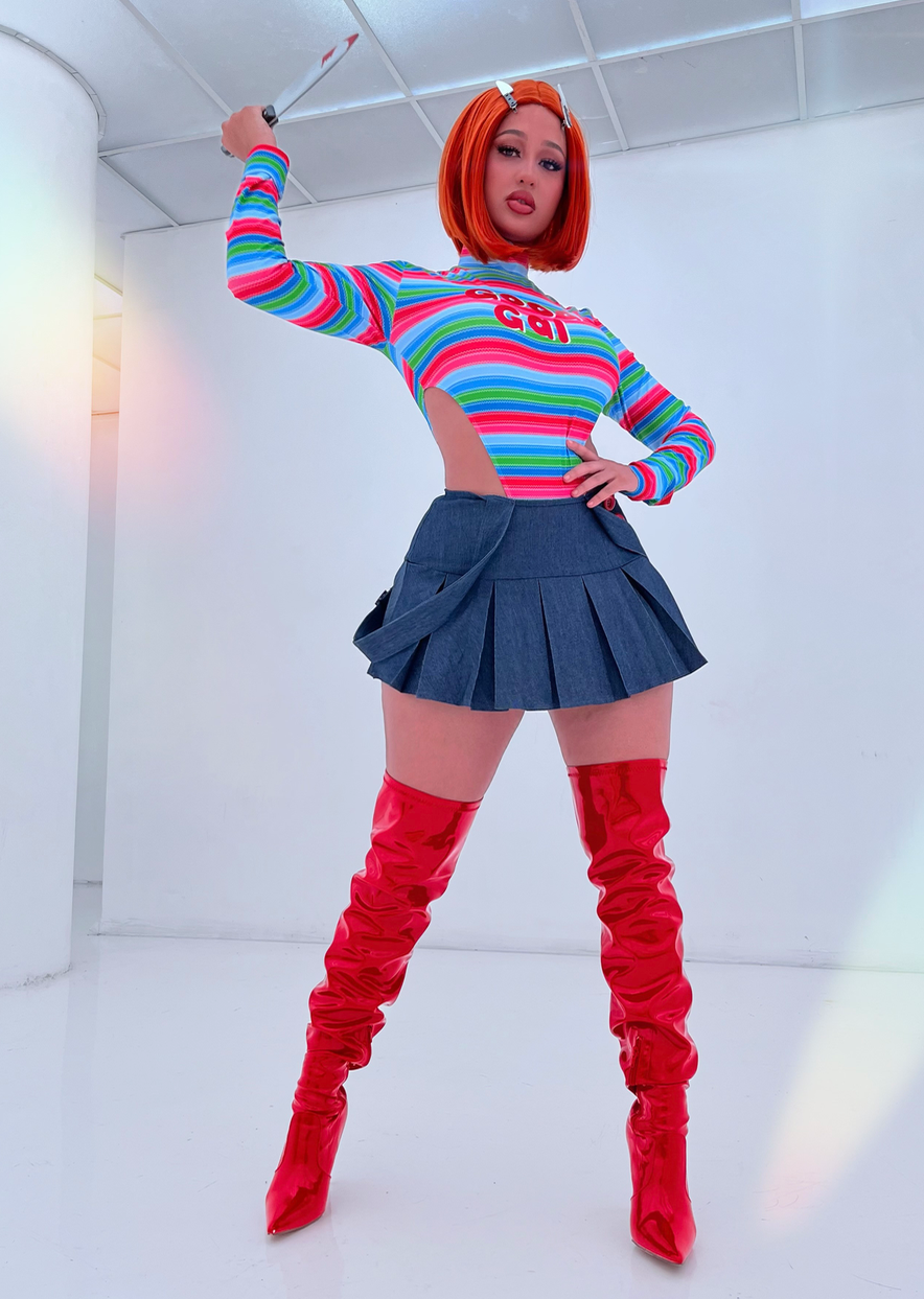 Model wearing shiny red over the knee boots paired with a colorful top and a pleated skirt