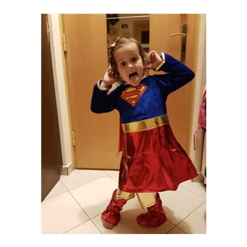 Child in a fun Supergirl Halloween Costume with blue top and red skirt, posing playfully at home