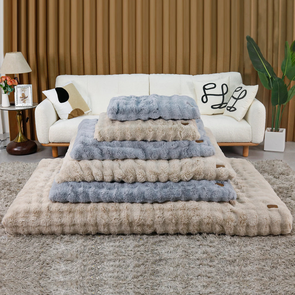Collection of ultra plush dog beds in various sizes stacked on a soft area rug